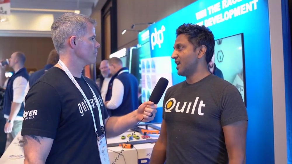 Two professionals engaged in discussion at the Bio-IT World 2024 event; a PTP member and a Quilt Data member converse amidst exhibition stands, surrounded by technology displays and conference attendees.