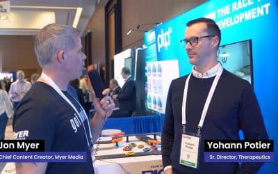 Yohann Potier being interviewed at the PTP booth during Bio-IT World 2024, with the conference setting visible in the background.